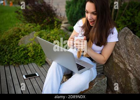 bella giovane donna freelancer a pranzo pausa seduta con laptop nel giardino Foto Stock