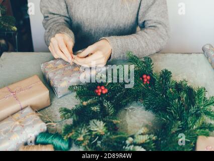 Donna fa una corona di abete e regali di imballaggio per Natale. Foto Stock