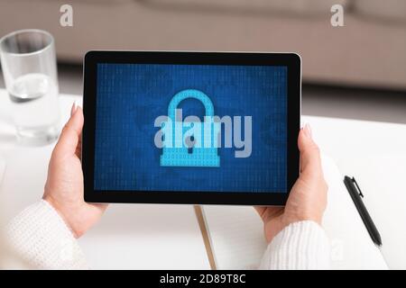 Donna che usa il tablet, icona a forma di lucchetto sullo schermo Foto Stock