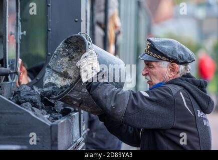 17 ottobre 2020, Meclemburgo-Pomerania occidentale, Klütz: Peter Bauchwitz dell'associazione Parkeisenbahn Wuhlheide di Berlino compila la locomotiva a brigata di 102 anni con carbone prima della partenza. Alla fine della stagione sul treno turistico da 600 millimetri, una storica locomotiva a vapore percorrerà il percorso. Il treno viaggerà a 20 chilometri all'ora sulla tratta di sei chilometri tra Klütz e Reppenhagen. La linea ferroviaria nel Meclemburgo nord-occidentale è stata aperta il 6 giugno 1905 come "Ferrovia Grand-Ducal-Meclemburgo Friedrich-Franz" ed è stata inizialmente utilizzata per il trasporto del grano fino al mil Foto Stock