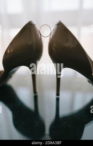 scarpe e anelli da sposa su un tavolo di vetro Foto Stock