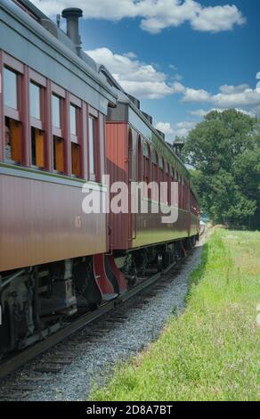 Treno a vapore per passeggeri che viaggia attraverso la campagna dalla vista del treno Un giorno di sole Foto Stock