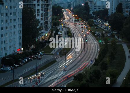 Ampia strada nel quartiere residenziale di Varsavia in serata con movimento luci offuscate delle auto Foto Stock