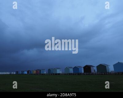 Leysdown, Kent, Regno Unito. 28 ottobre 2020. UK Weather: Nuvole di pioggia oscure minacciose si profilano sulle capanne della spiaggia a Leysdown, Kent questa sera. Credit: James Bell/Alamy Live News Foto Stock