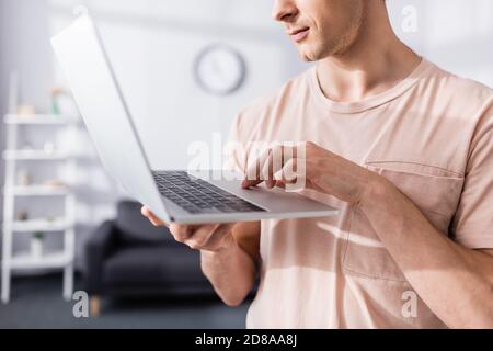 Vista ritagliata del freelance che tiene e scrive sul notebook a casa, guadagnando il concetto online Foto Stock