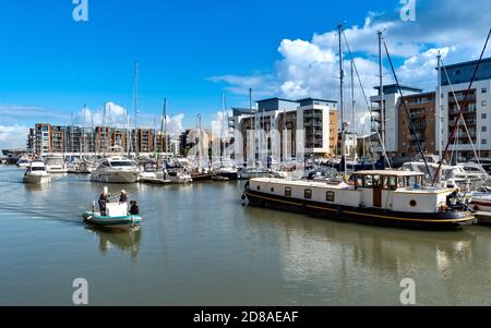 PORTISHEAD BRISTOL SOMERSET ENGLAND IL PORTO TURISTICO CON DUE PICCOLE IMBARCAZIONI PASSANDO PER GLI YACHT ORMEGGIATI E LA CASA GALLEGGIANTE Foto Stock