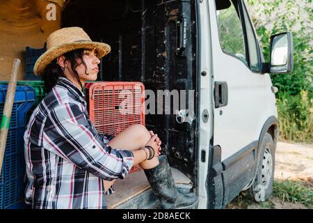 Giovane donna contadina che riposa in un furgone al campo di coltura Foto Stock