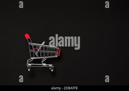 Concetto di vendita del Black Friday. Carrello vuoto rosso su sfondo scuro. Shopping, commercio e mockup di vendita. Disposizione piatta composizione minima con spac copia Foto Stock