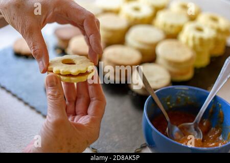 Nonna making tradizionale tedesco spitzbuben weihnachtskekse linzer biscotti riempito con marmellata Foto Stock
