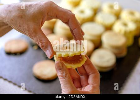 Nonna making tradizionale tedesco spitzbuben weihnachtskekse linzer biscotti riempito con marmellata Foto Stock