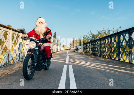 babbo natale che guida una moto sulla strada Foto Stock