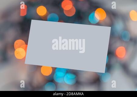 Biglietto da visita bianco vuoto sullo sfondo della luce di Natale Garland. Atmosfera festosa e vibes. Stazionario per l'identità di branding. Foto Stock
