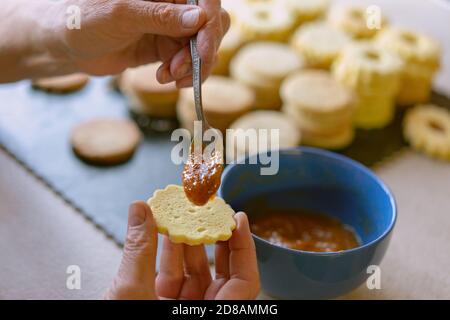 Nonna making tradizionale tedesco spitzbuben weihnachtskekse linzer biscotti riempito con marmellata Foto Stock