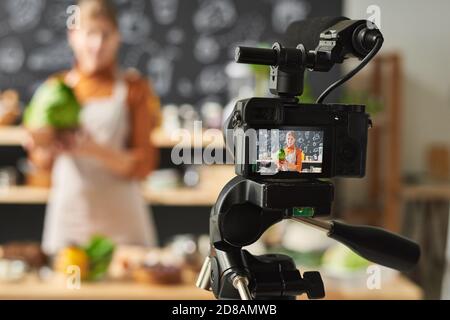 Giovane donna che tiene verdura e registra il video sul cibo per il suo blog Foto Stock