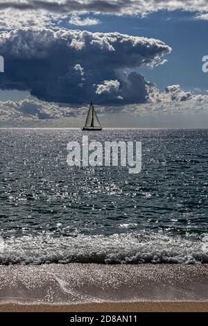 Cielo drammatico sul Mar Mediterraneo, Costa Brav in Spagna. Barca a vela nuotare lontano un modo. Foto Stock