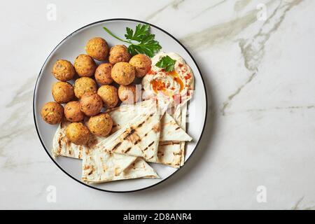 Falafel fritte mediterranee, di ceci con spezie: Coriandolo, cumino con bagno di hummus e pane piatto su un piatto, vista dall'alto, primo piano Foto Stock