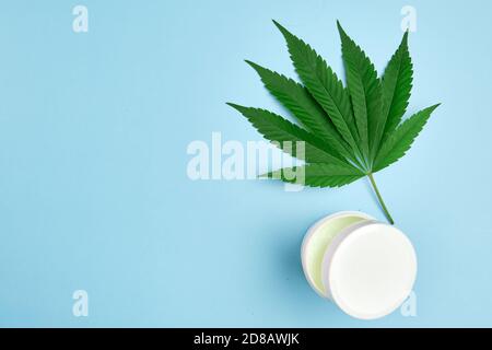 Foglia di cannabis e confezione di plastica o barattolo con copia spazio con olio di canapa contenente crema Foto Stock