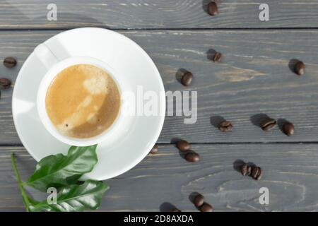 Tazza di caffè espresso con chicchi di caffè sparsi su sfondo di legno con spazio per il testo. Poster. Foto Stock