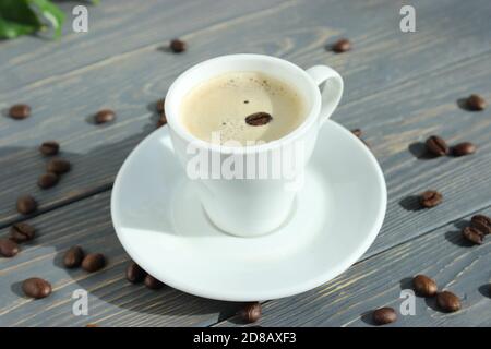 Tazza di caffè espresso con chicchi di caffè sparsi su sfondo di legno con spazio per il testo. Poster. Foto Stock