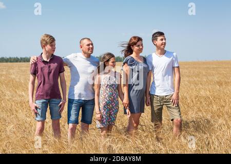 Grande famiglia di padre, madre, due fratelli e sorella in linea su un campo di grano, ritratto a lunghezza intera Foto Stock