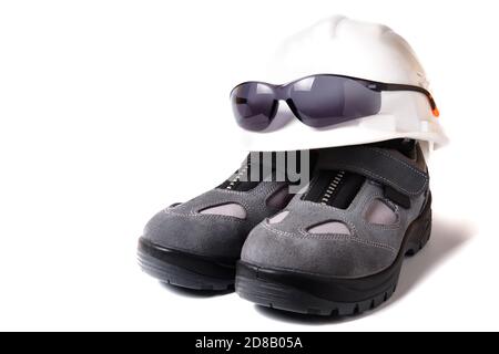 HardHat, occhiali protettivi e paio di nuove scarpe protettive isolate su bianco Foto Stock