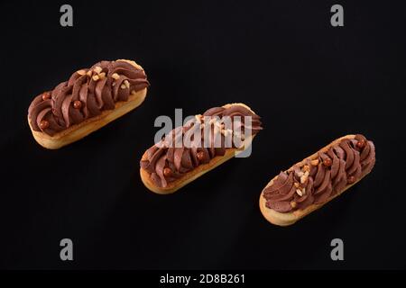 Biscotti frollini con panna di cioccolato marrone montata con mascarpone. Vista dall'alto di tre dolci freschi fatti in casa isolati su sfondo nero. Concetto di dolci, industria alimentare. Foto Stock