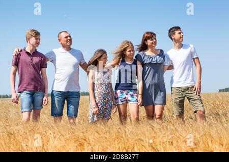 Più famiglie di bambini di agricoltori in fila su campi di grano giallo, bambini di età teen, due fratelli e sorelle Foto Stock