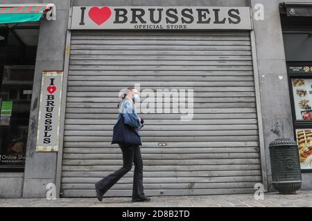 Bruxelles, Belgio. 28 Ott 2020. Una donna che indossa una maschera passa davanti a un negozio chiuso a Bruxelles, Belgio, il 28 ottobre 2020. L'istituto di salute belga Sciensano ha rilasciato mercoledì la cifra di morte COVID-19 di 104 registrata il lunedì, il numero più alto giornaliero dall'inizio della seconda ondata. Credit: Zheng Huansong/Xinhua/Alamy Live News Foto Stock