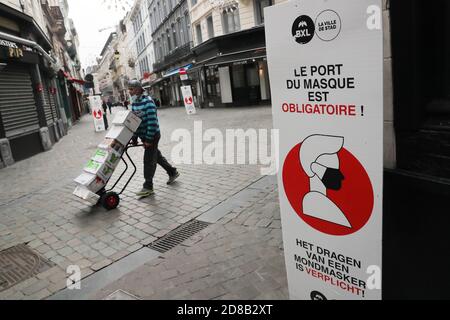 Bruxelles, Belgio. 28 Ott 2020. Un uomo passa accanto a un cartello che ricorda alle persone di indossare maschere a Bruxelles, Belgio, il 28 ottobre 2020. L'istituto di salute belga Sciensano ha rilasciato mercoledì la cifra di morte COVID-19 di 104 registrata il lunedì, il numero più alto giornaliero dall'inizio della seconda ondata. Credit: Zheng Huansong/Xinhua/Alamy Live News Foto Stock