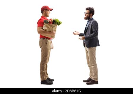 Foto di profilo a lunghezza intera di un tipo di consegna che consegna un borsa della spesa ad un uomo bearded isolato su sfondo bianco Foto Stock