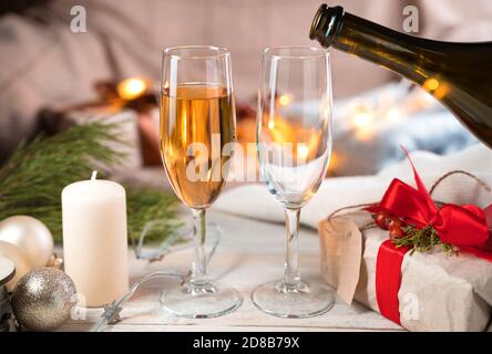Versare champagne in bicchieri su sfondo natalizio. Foto Stock