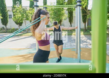 Giovane donna e uomo che praticano la calistenica in un parco giorno di sole Foto Stock