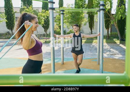 Giovane donna e uomo che praticano la calistenica in un parco giorno di sole Foto Stock