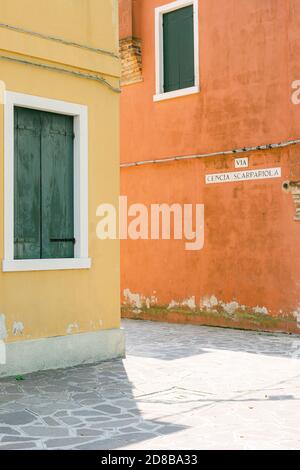 Due case a Burano, in Italia, con pareti gialle e pareti arancioni, in una giornata di sole estivo Foto Stock