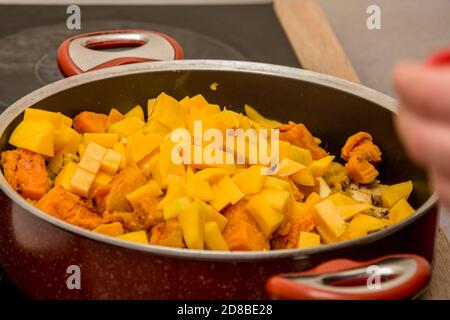 Preparare il composto di mango, tofu e patata dolce in rosso la pentola Foto Stock