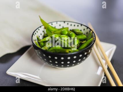 Fagioli di edamame in una ciotola con bastoncini di legno. Soia verde fresca e sana. Foto Stock