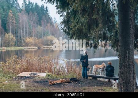 Una coppia siede su un albero con un cane, sul lago. Foto Stock