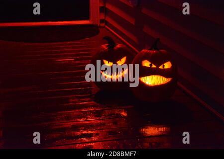 Le zucche intagliate brillano sul portico anteriore di una casa durante Halloween. Foto Stock