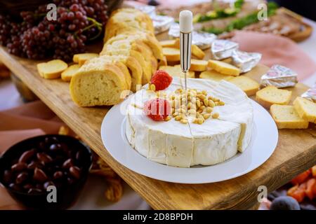 Formaggio Brie con noci, pane e uva su tavola rustica in legno. Foto Stock