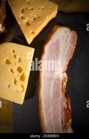 Formaggio e pancetta su un tagliere di pietra Foto Stock