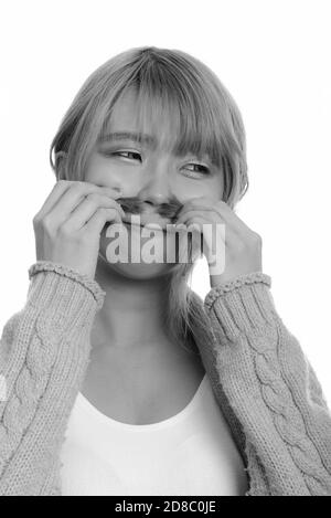 Giovane donna asiatica annusare i suoi capelli mentre guarda lontano Foto Stock