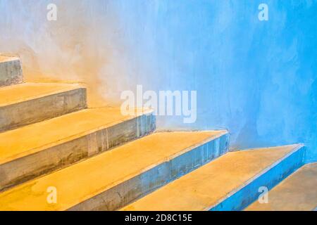 Scale di cemento intorno ad un edificio rotondo con un gradiente di colore dal giallo caldo al blu freddo Foto Stock