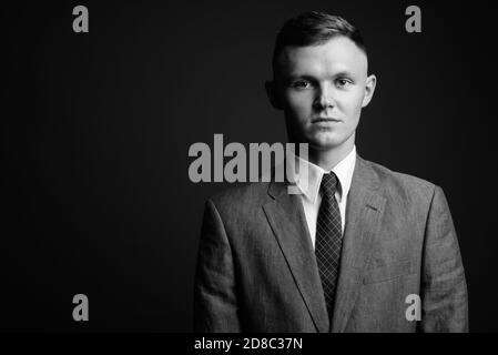 Giovane imprenditore indossare tuta contro uno sfondo grigio Foto Stock