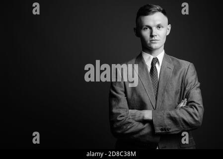 Giovane imprenditore indossare tuta contro uno sfondo grigio Foto Stock