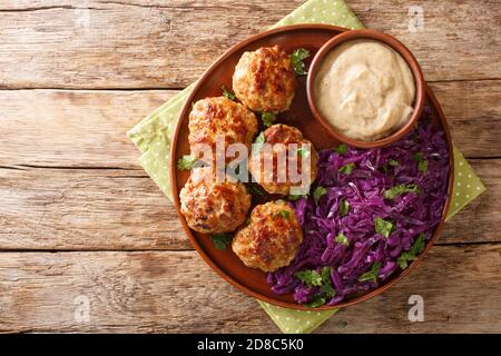 Le polpette di Frikadeller o Danish sono polpette salate servite con salsa cremosa e stufate il cavolo rosso da vicino nel piatto sul tavolo. Orizzontale Foto Stock