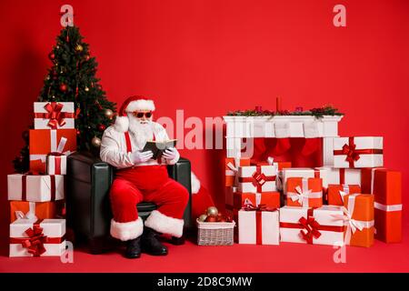Ritratto del suo attraente funky grasso sovrappeso allegro messo a fuoco Intelligente Babbo Natale seduta in poltrona soggiorno lettura libro isolato luminoso Foto Stock