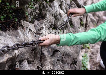 Donna che tiene una catena con le mani mentre sale la montagna . Foto Stock