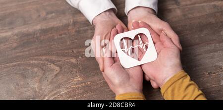 Concetto di assicurazione sanitaria con il battito cardiaco della carta nelle mani Foto Stock