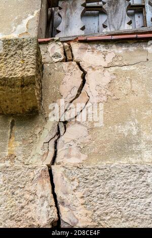 muro distrutto dell'edificio da vicino. Crepe e fratture sotto una finestra di legno. Il concetto delle conseguenze delle guerre e dei conflitti armati Foto Stock