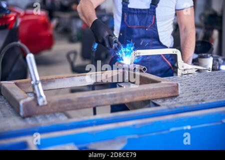 Meccanico che utilizza la torcia di saldatura in officina di riparazione automatica Foto Stock